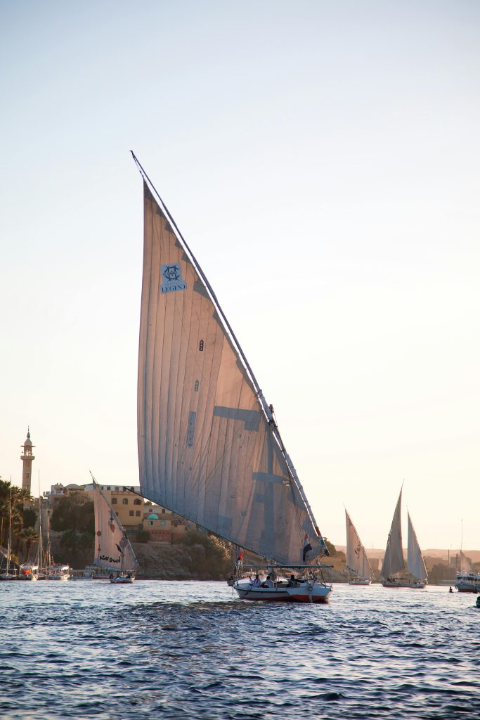Scenic view of traditional sailboats on the Nile River during sunset, capturing serene Egyptian landscape.