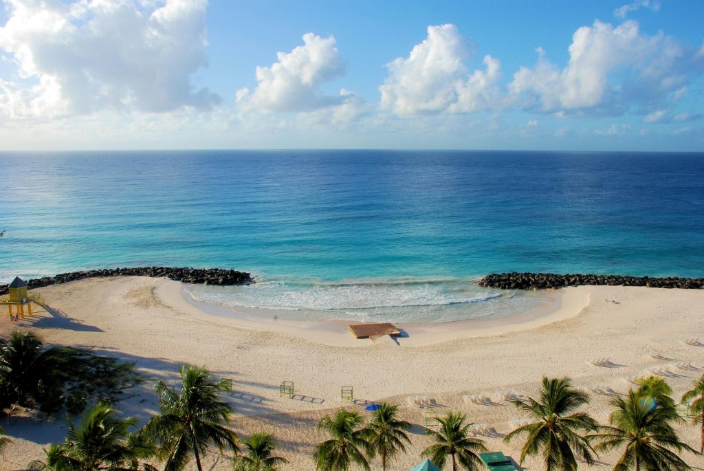 A serene tropical beach with white sand, palm trees, and crystal clear blue ocean waters under a vibrant sky.