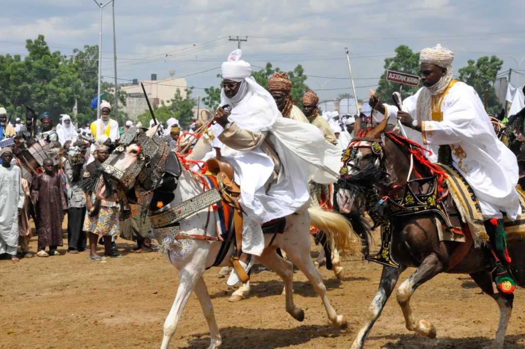 Colorful display of the Durbar festival in Kano, Nigeria, featuring traditional attire and horsemen.