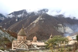 Historic Dadivank Monastery set against misty Armenian mountains in fall.